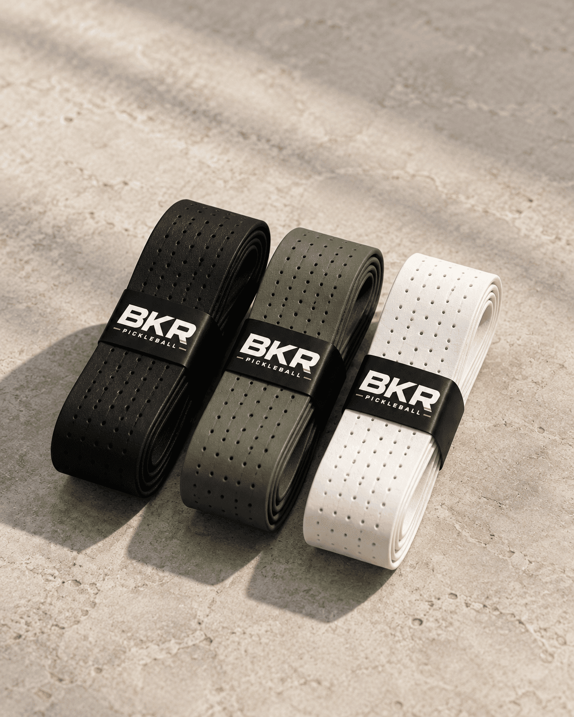 Three BKR overgrips in black, olive and white, rolled and banded