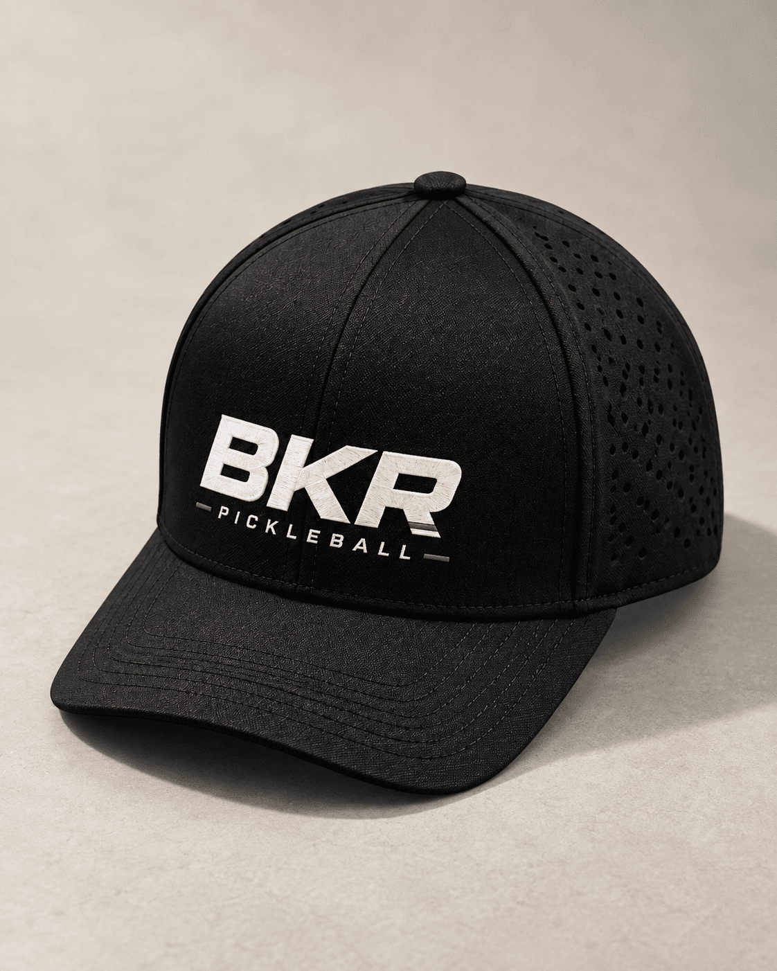 Black perforated BKR cap with white embroidery on pale limestone