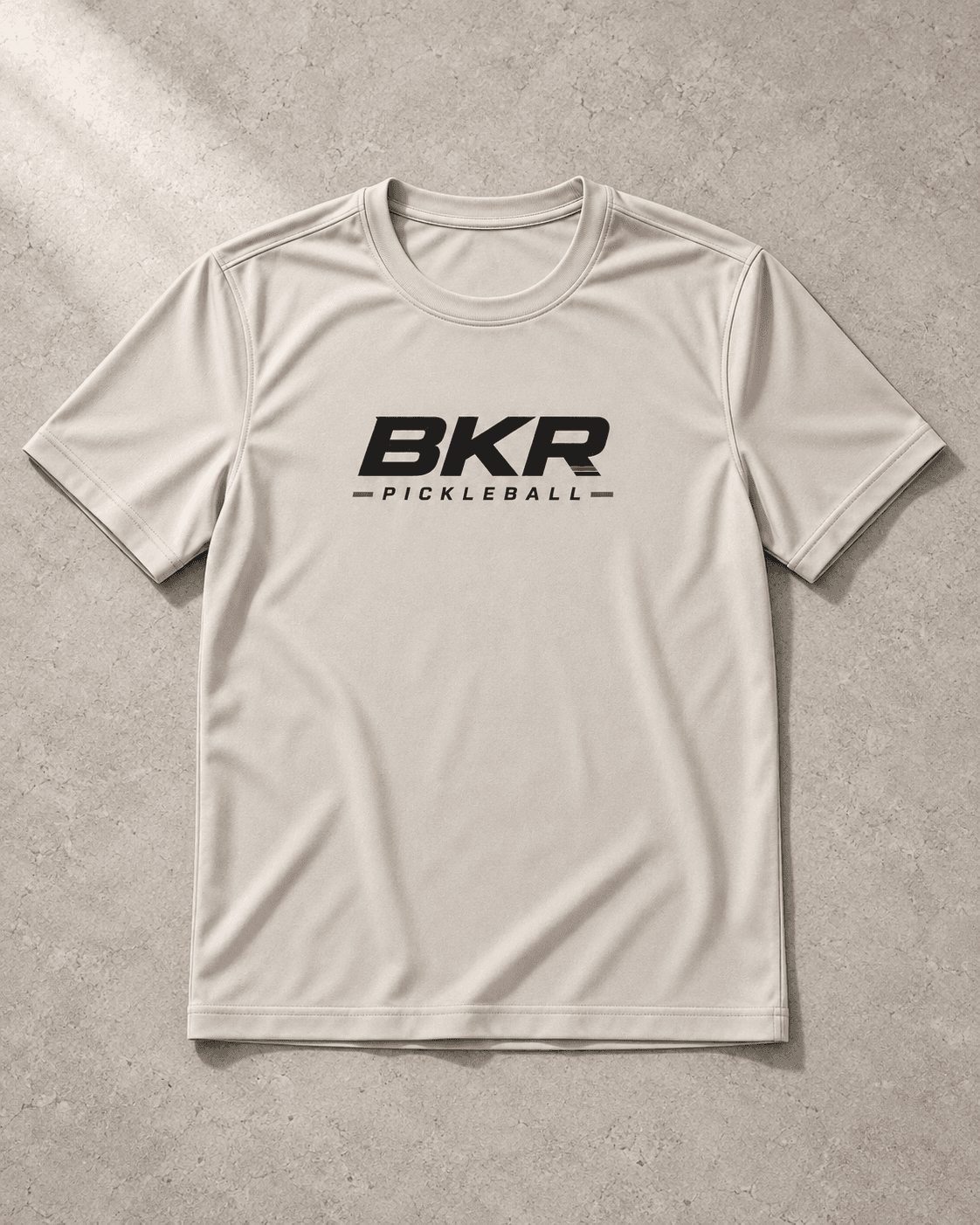 Bone BKR performance tee with black chest logo on pale limestone